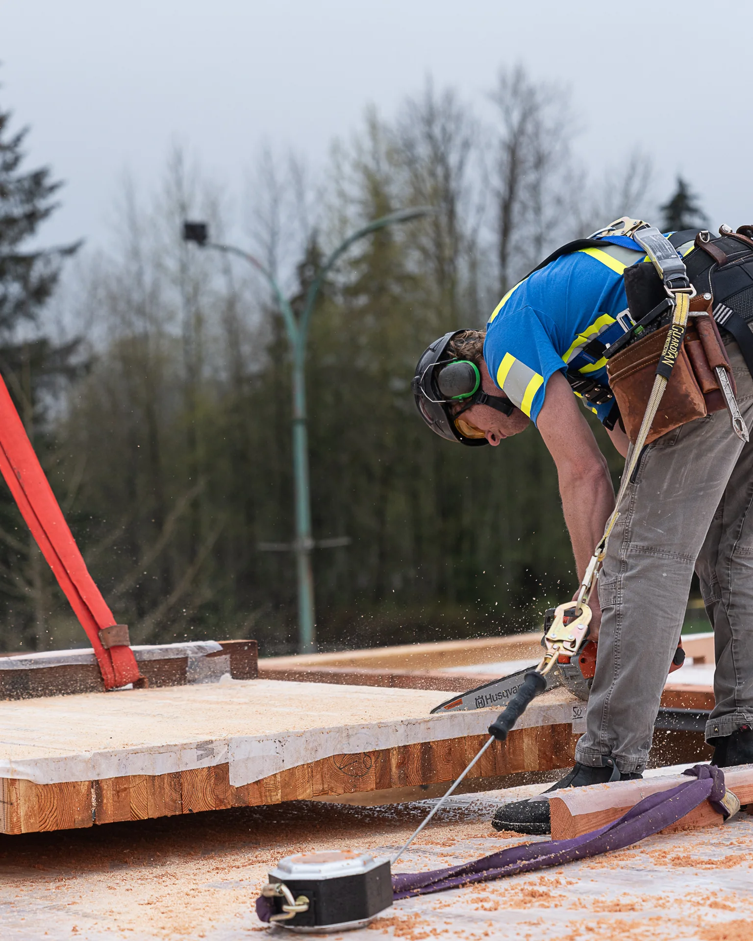 A builder bent over a saw, cutting the edge of a timber panel