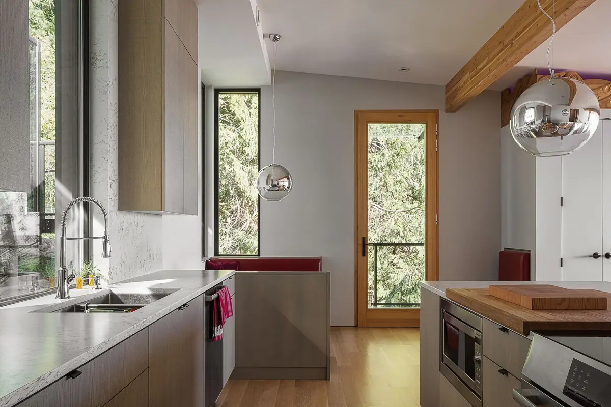 Galley kitchen with chrome globe pendants and a wood door opening to the trees