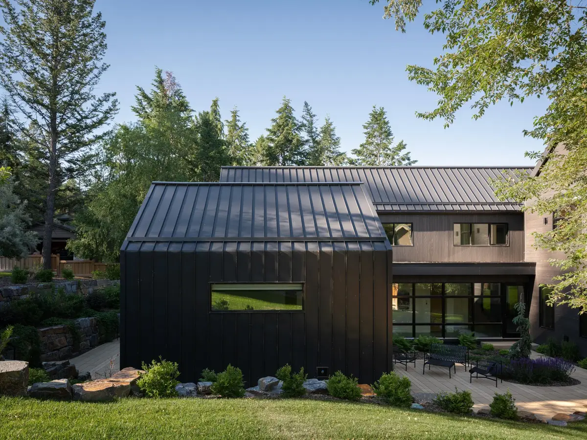 A dark clad volume with one long window in evening light, lawn across the foreground
