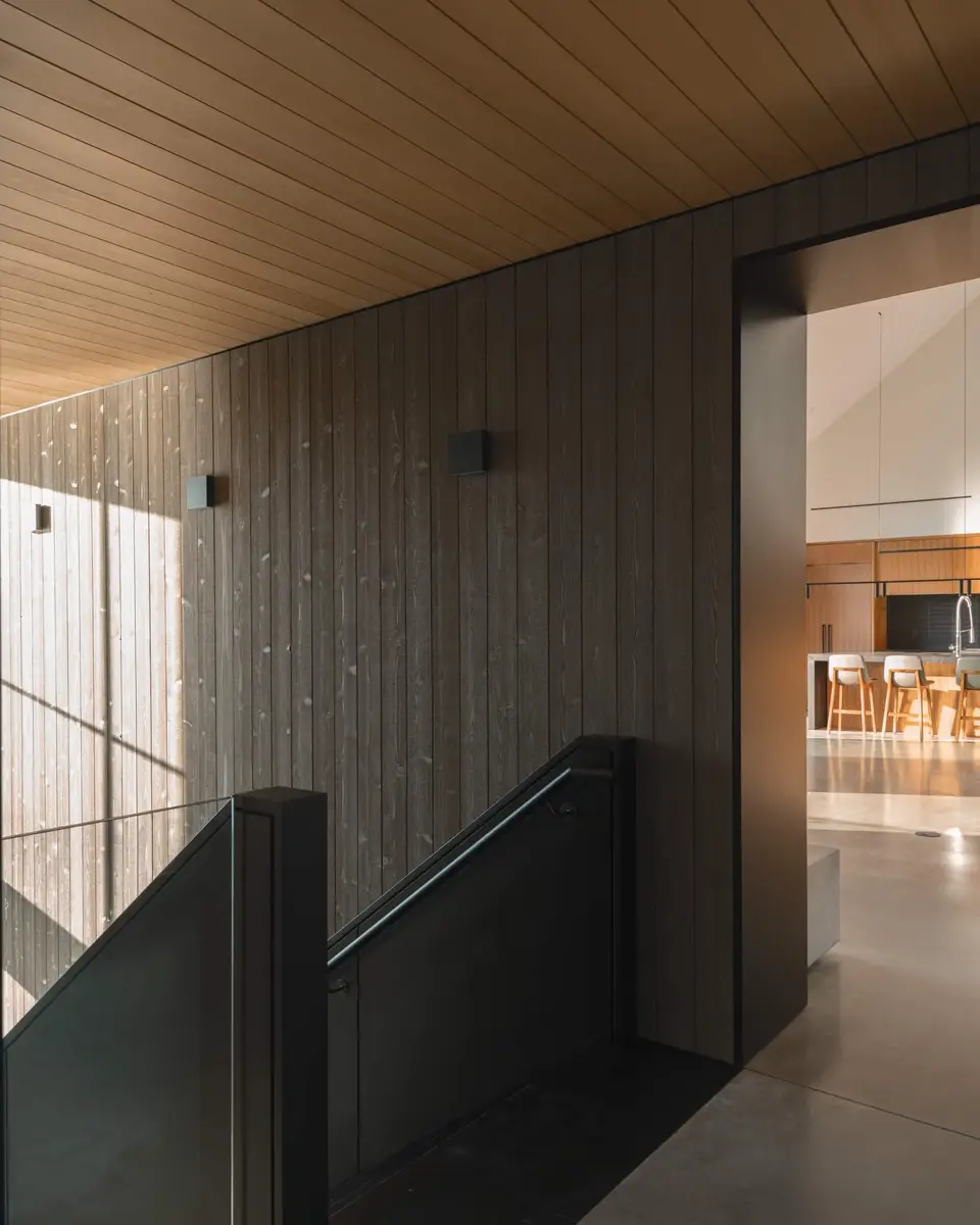 Landing beside a dark board wall, an opening through to the kitchen and its stools