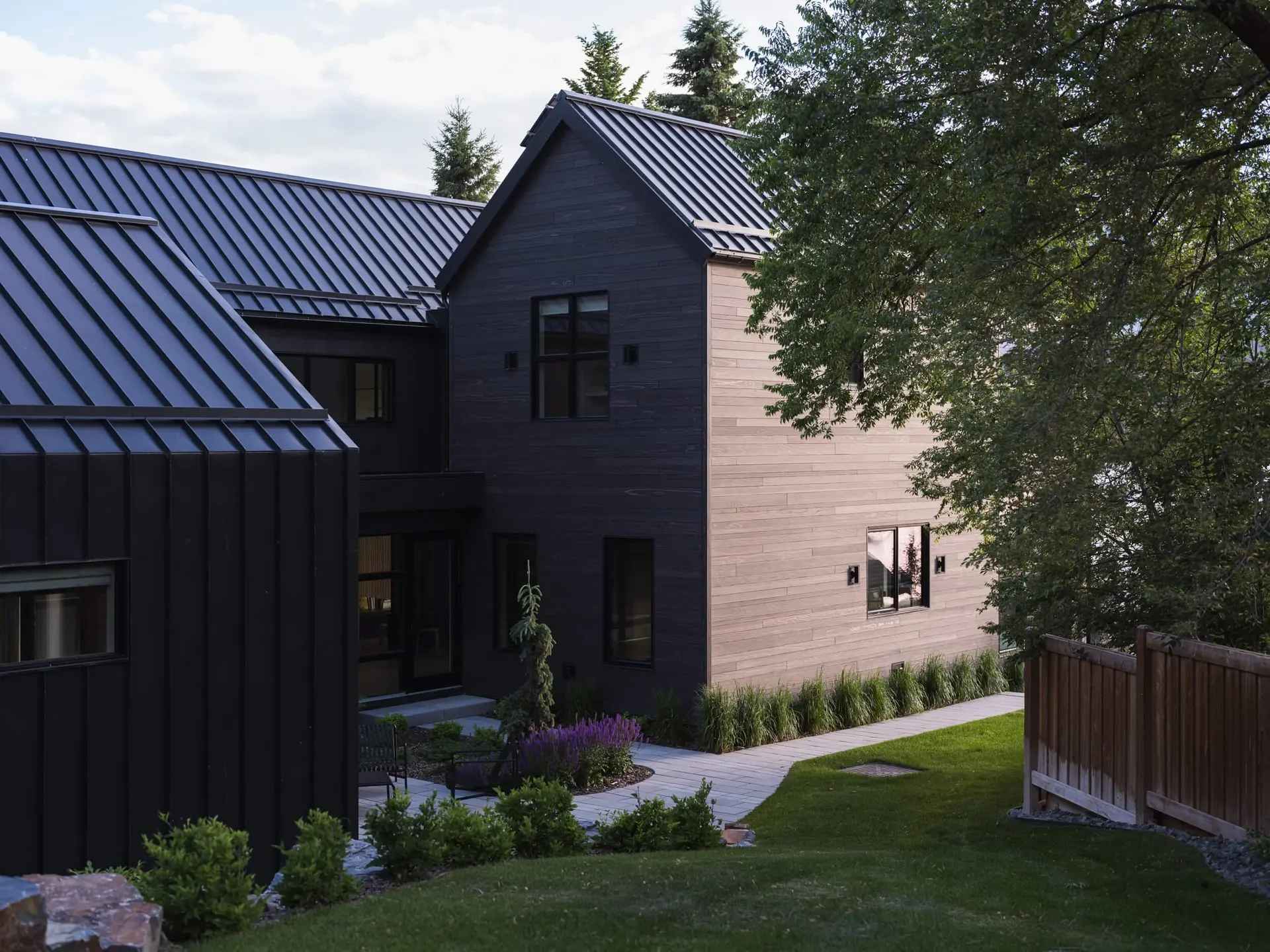 Evening light on the gables and the lawn, a fence and planting at the edge