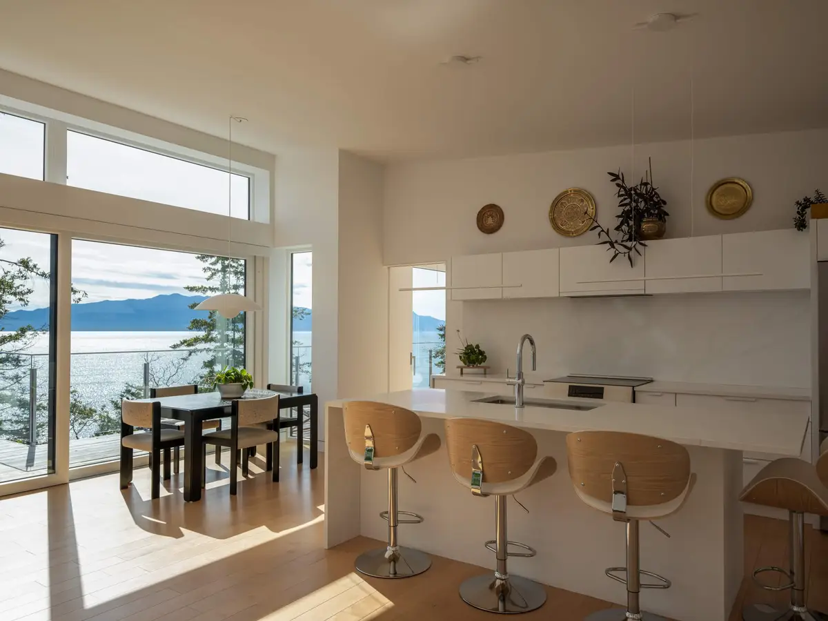 Kitchen island and stools looking past the dining table to the water and far shore