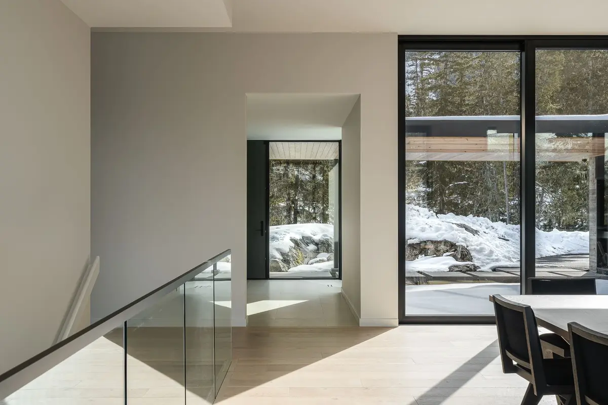 Upper landing with a glass balustrade, looking through to a window seat and forest