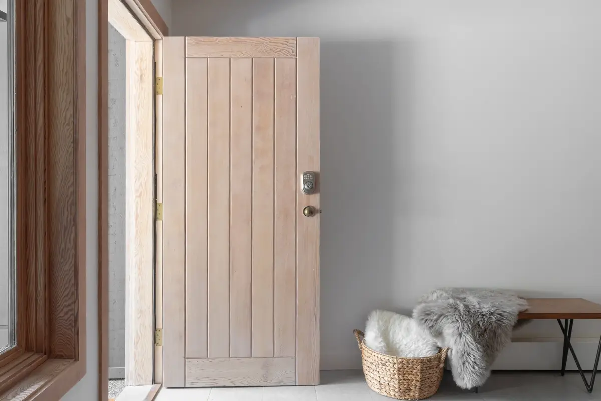 Entry door standing open onto the walk, a sheepskin over a basket beside a bench