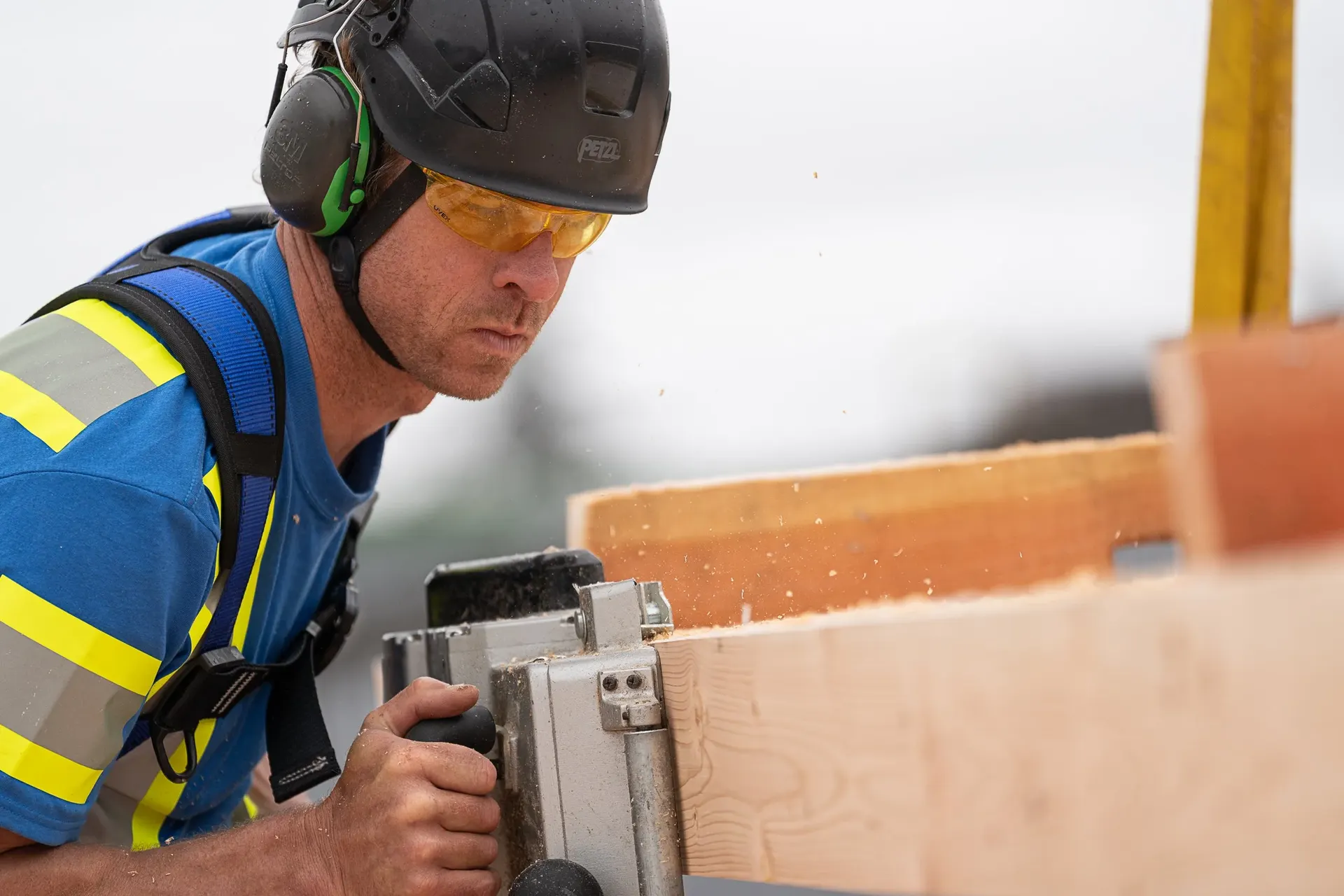 A worker cutting mass timber with a saw