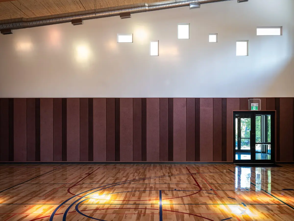 Gymnasium end wall in dark panelling with a glazed door and court lines below