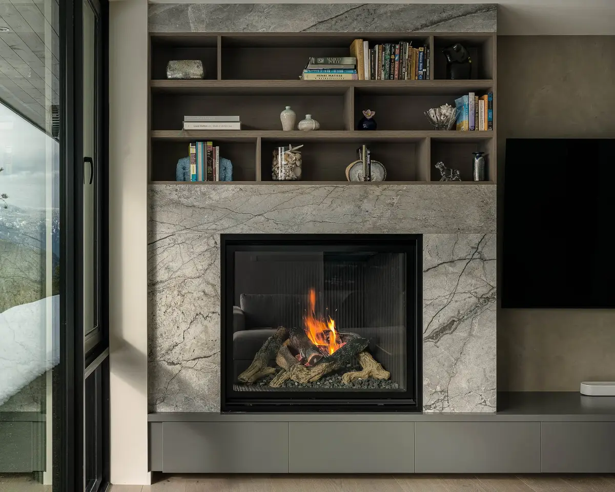 Lit fireplace in a stone surround with open shelving above
