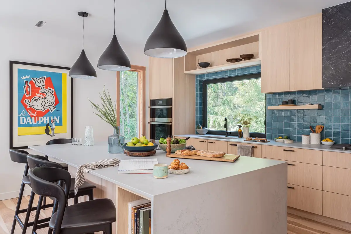 Kitchen and island seen past a framed poster, produce and a book on the counter