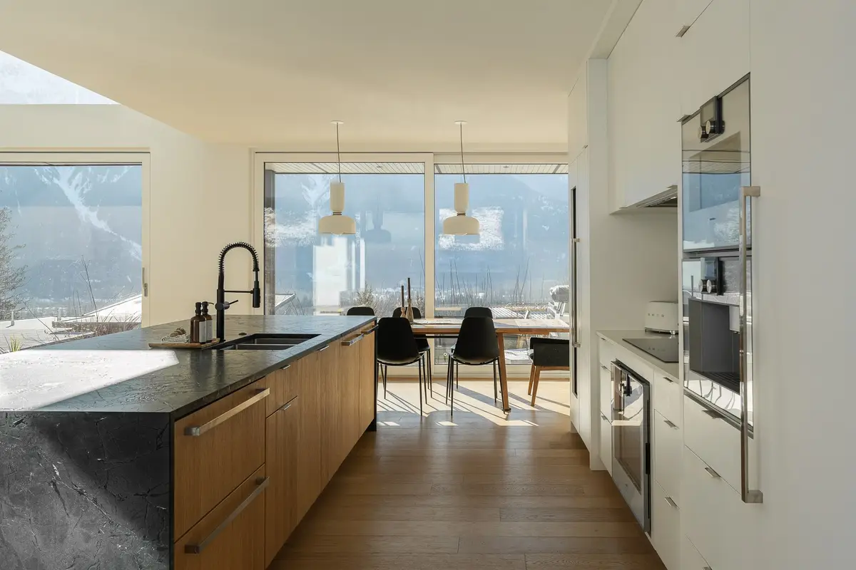 Along the length of the island to a dining table and glazing onto the mountain