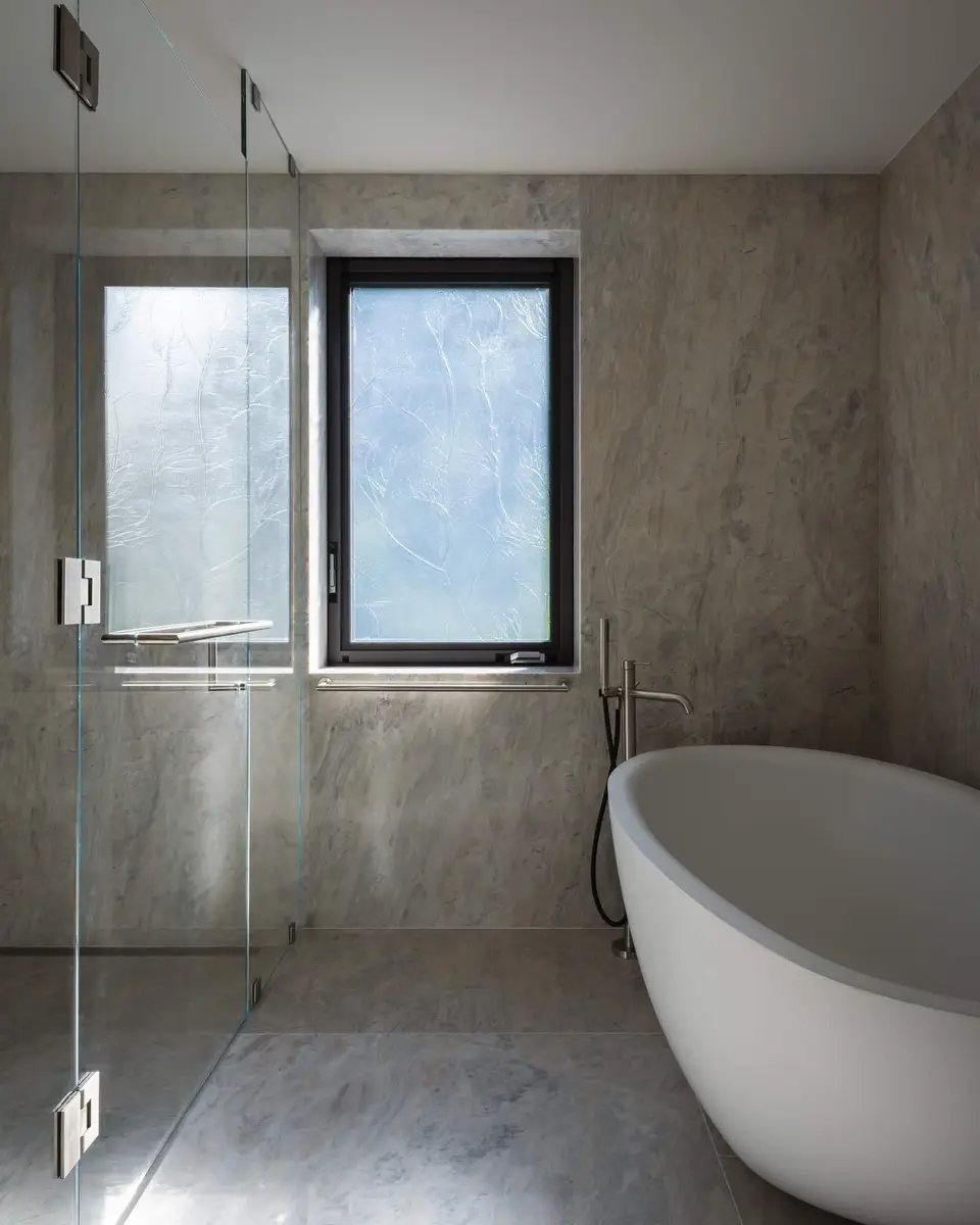 Freestanding tub under a window with the glass shower enclosure standing in front