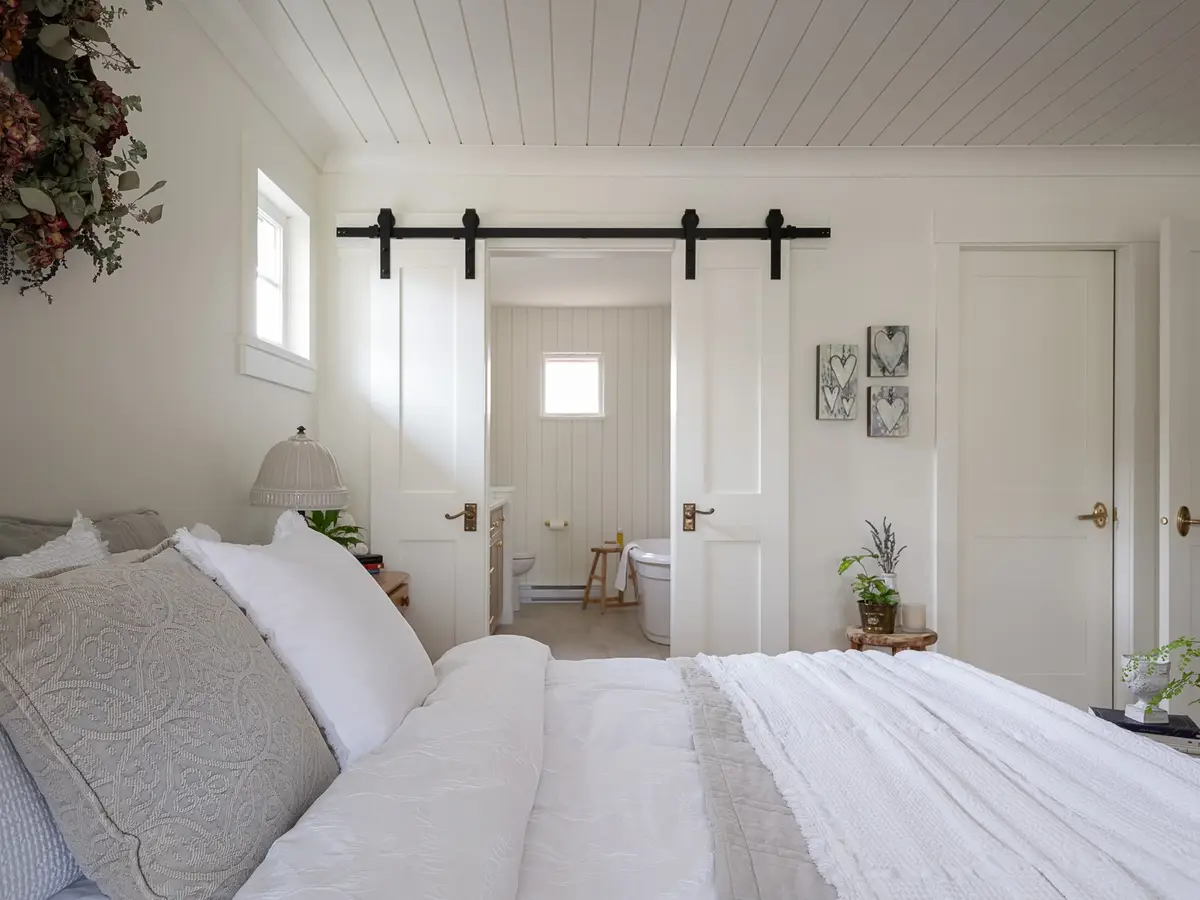 Bedroom with a sliding door on a black track standing open to a bathroom