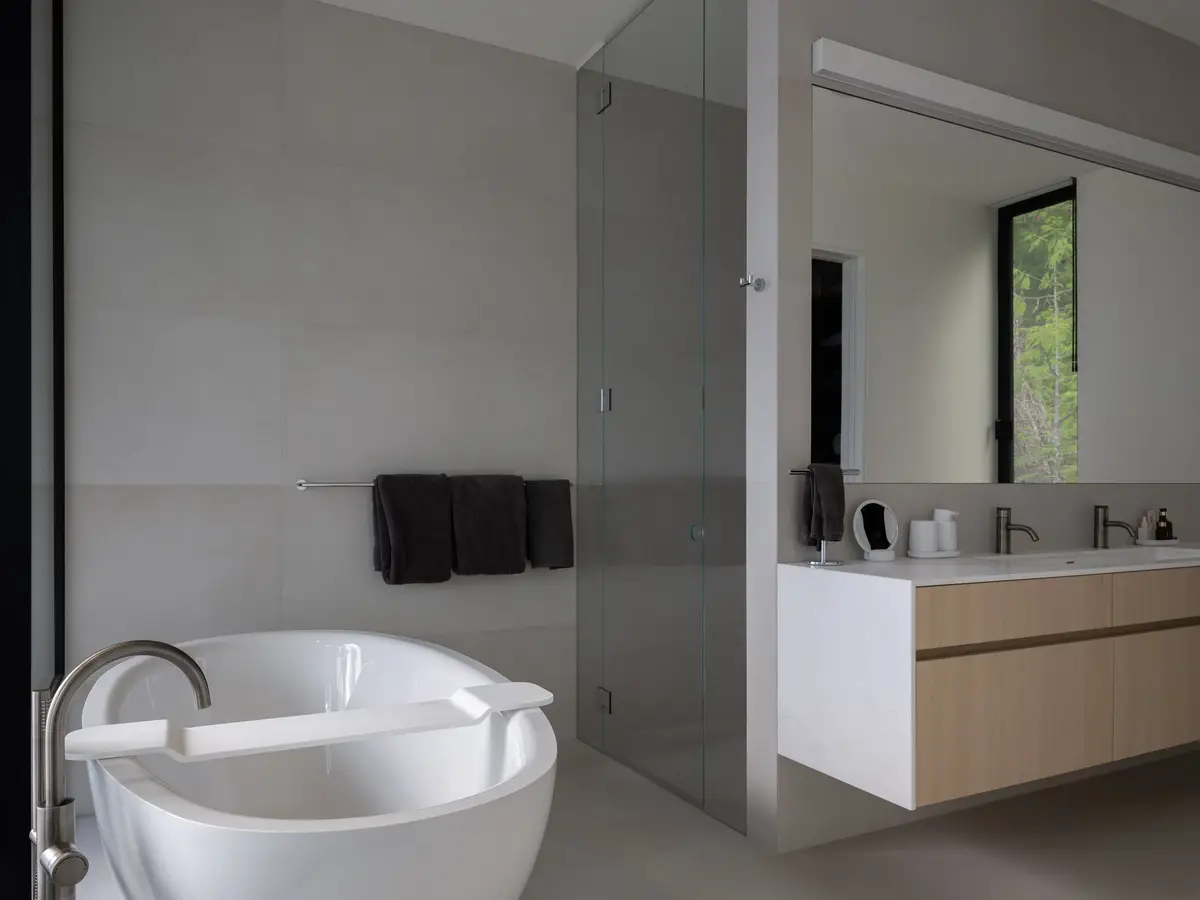 Freestanding tub beside a glass shower, dark towels on a rail and a mirrored vanity