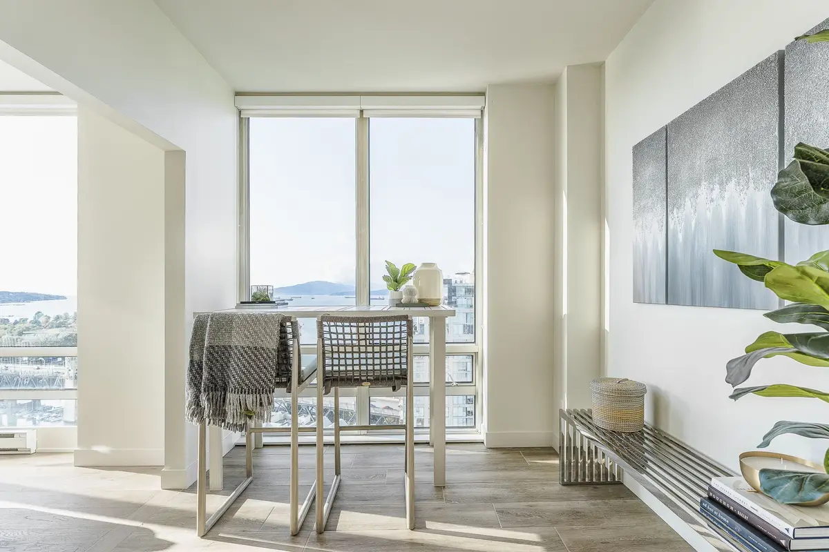A high table and stools drawn up to the window, city rooftops and water behind