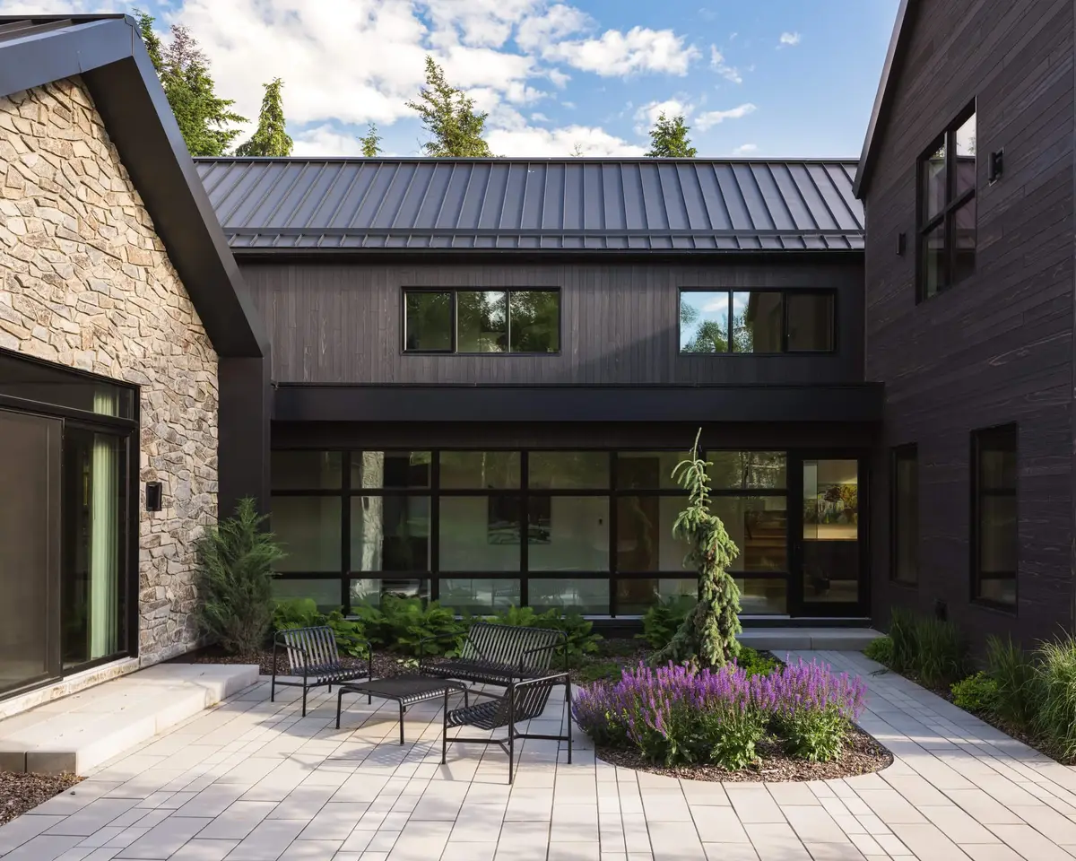 Courtyard with two benches and purple planting, glazing and dark siding on three sides