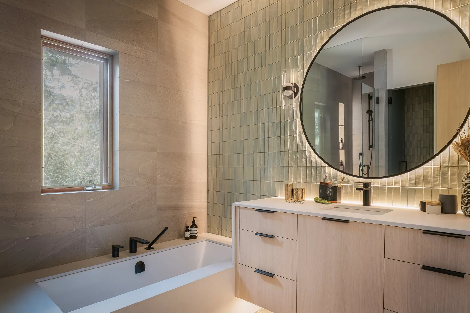 Bathroom with a tub at the window and a round mirror over the vanity