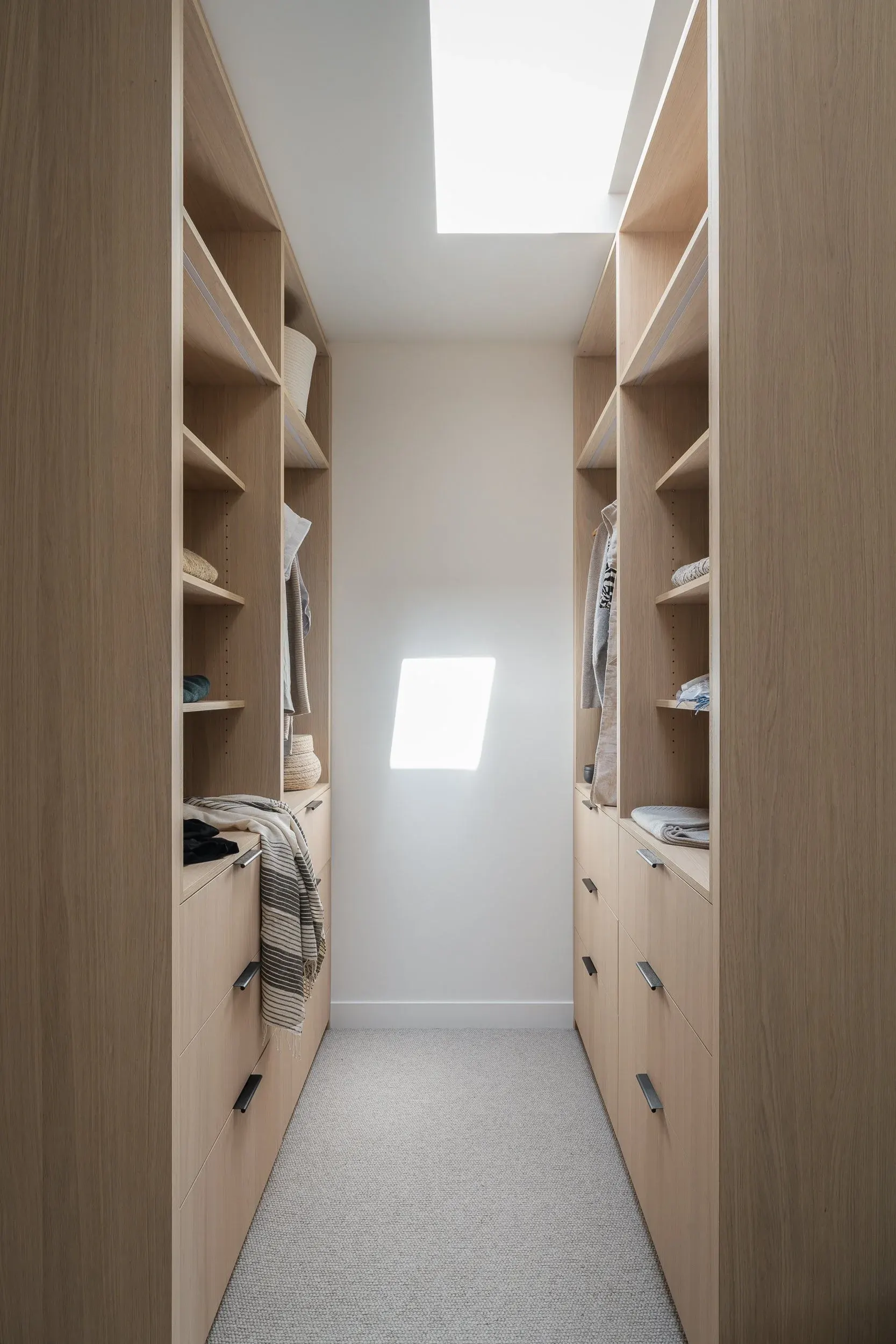 Walk through closet of open shelves and drawers, a skylight above the run