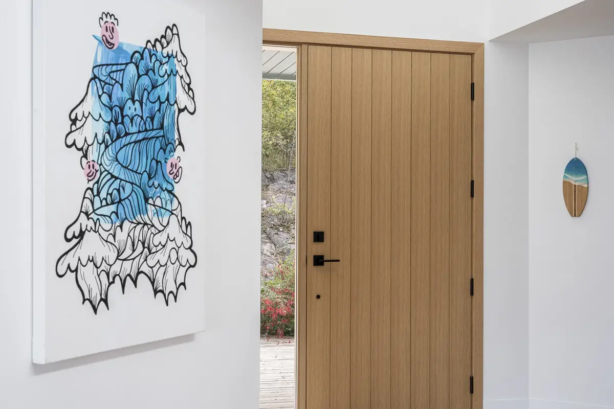 Entry hall with a large blue and black painting beside a vertical board wood door
