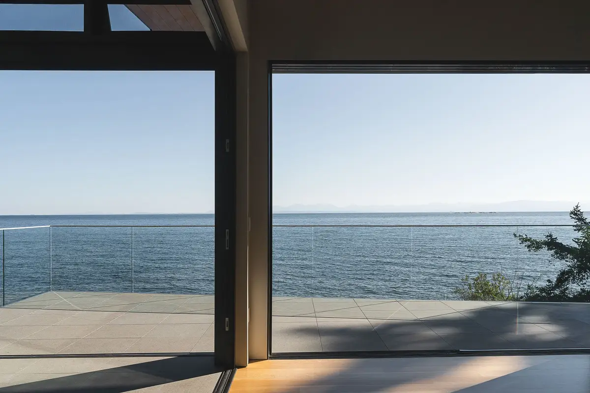 Dark interior framing the water through a wide opening onto the terrace