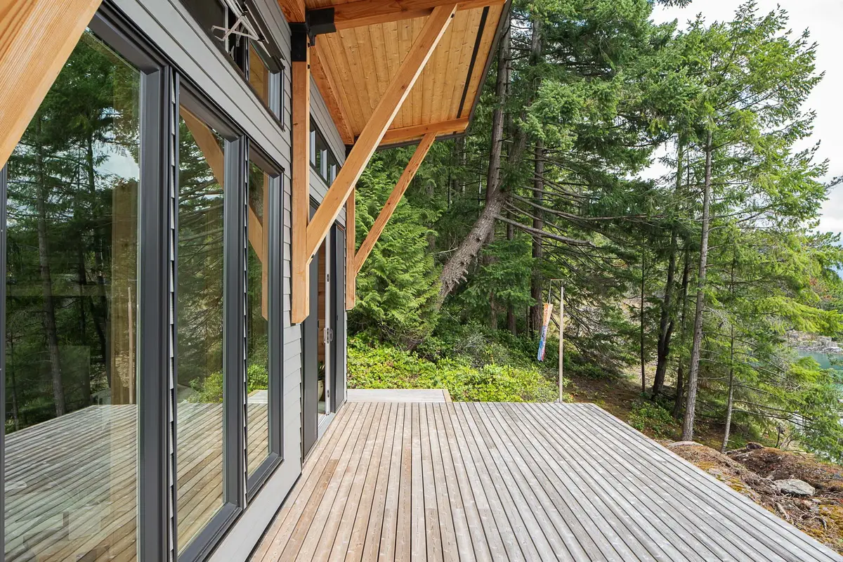 Deck under a wood soffit, sliding glass along the wall and forest beyond the edge