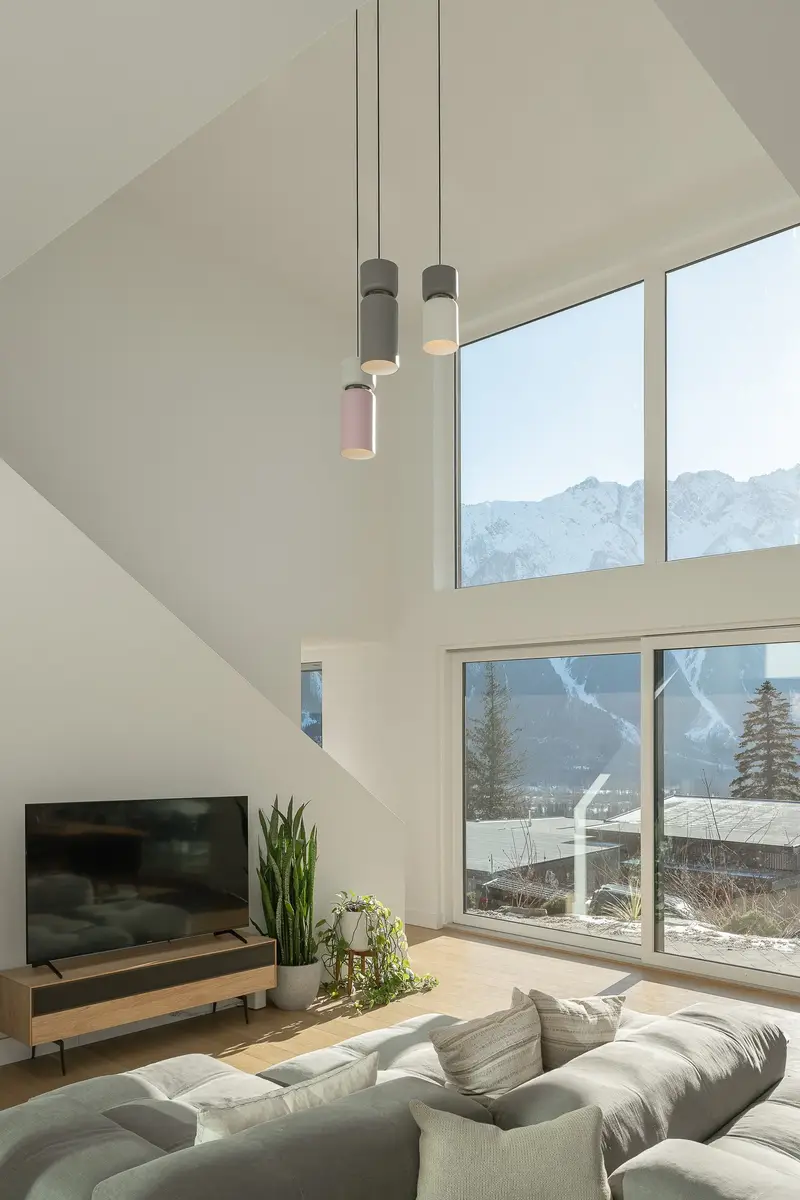 Double height living room, three pendants and tall glazing framing a snow covered mountain