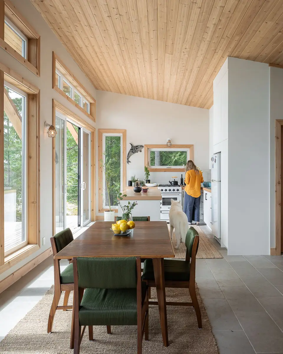 Dining table set for a meal, the kitchen beyond, a person and a dog at the counter