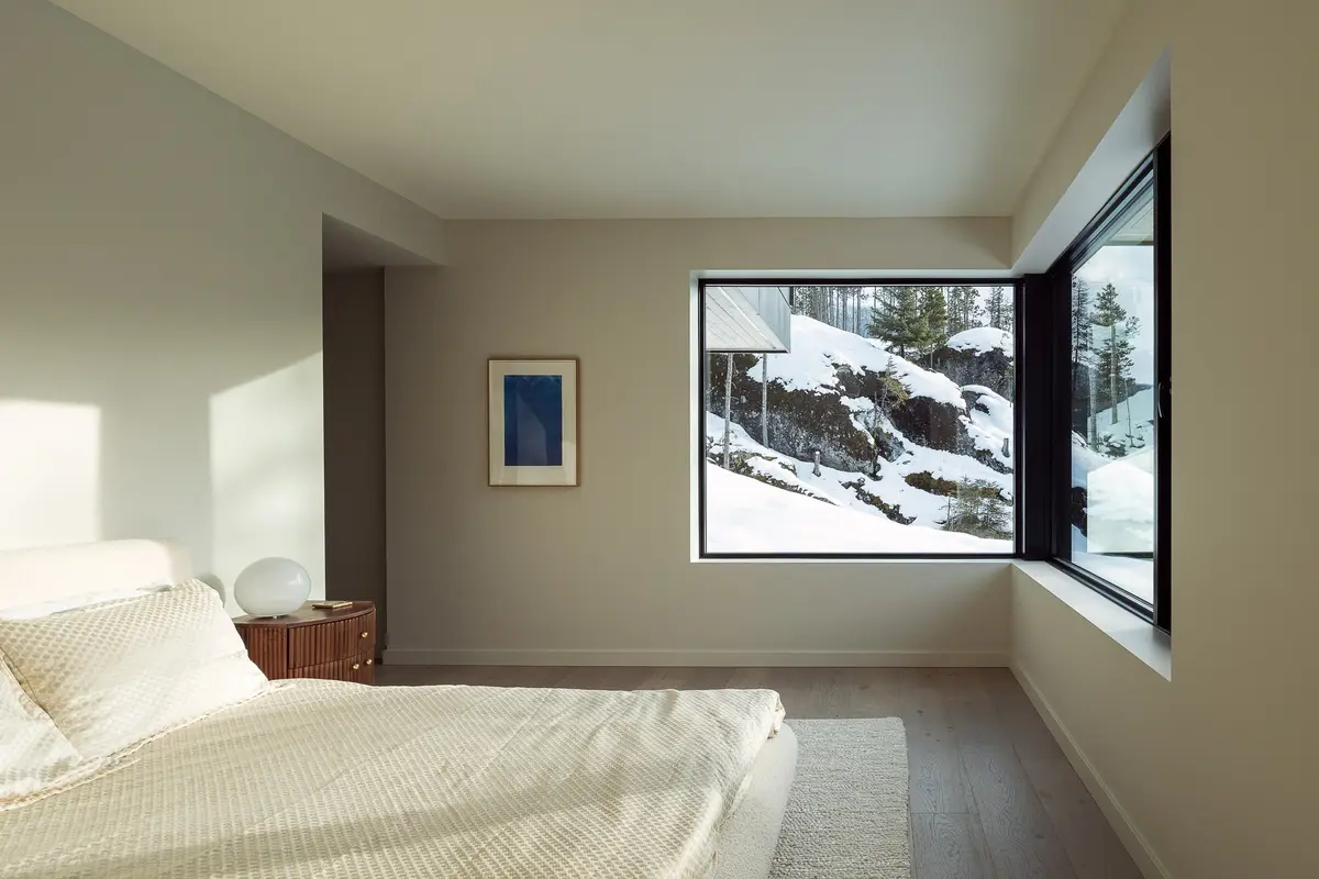 Bedroom with a corner window framing the snowy slope, a framed work on the wall