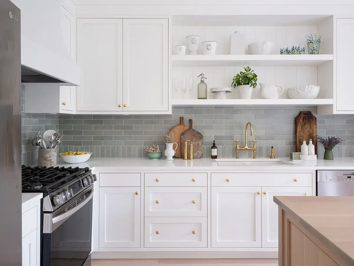 Kitchen under a plank ceiling, ribbed glass pendants over a pale wood island, green tiled wall behind