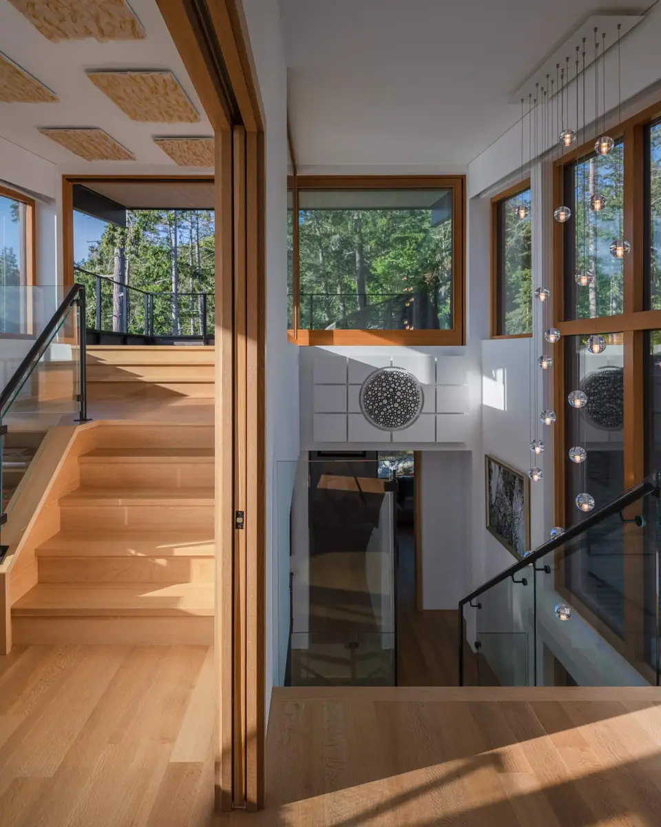 Upper hall behind a glass balustrade, woven ceiling panels and windows to the trees