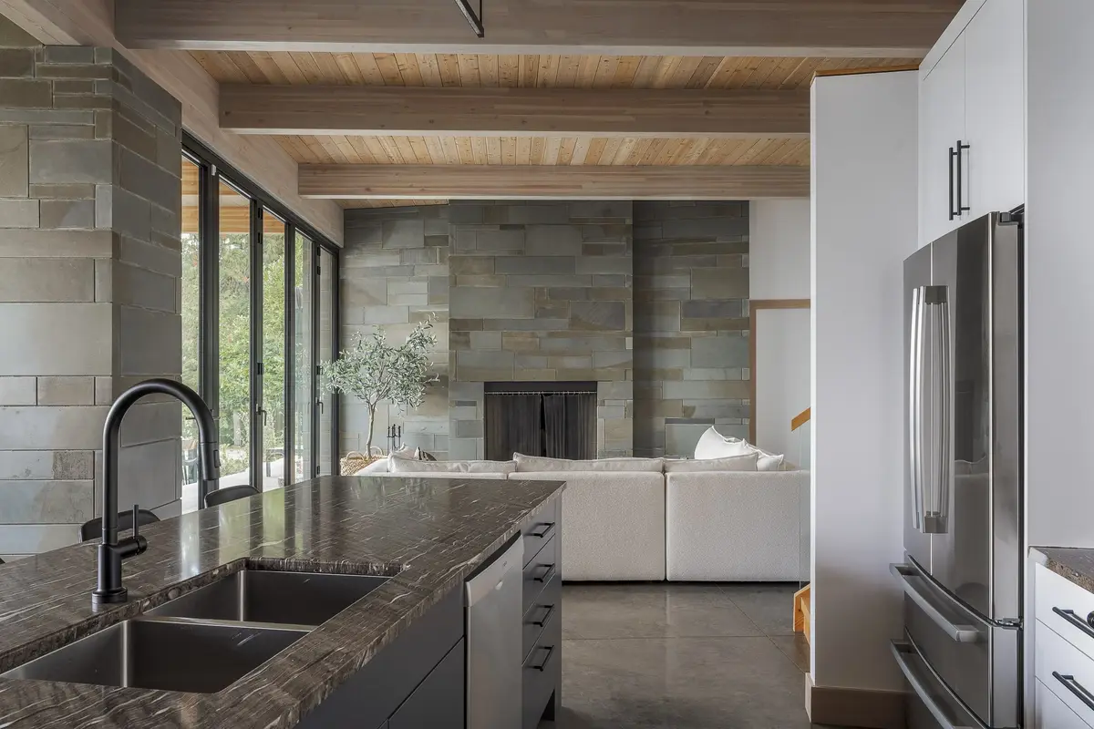 Second kitchen island with sinks, a stone faced fireplace and sectional beyond