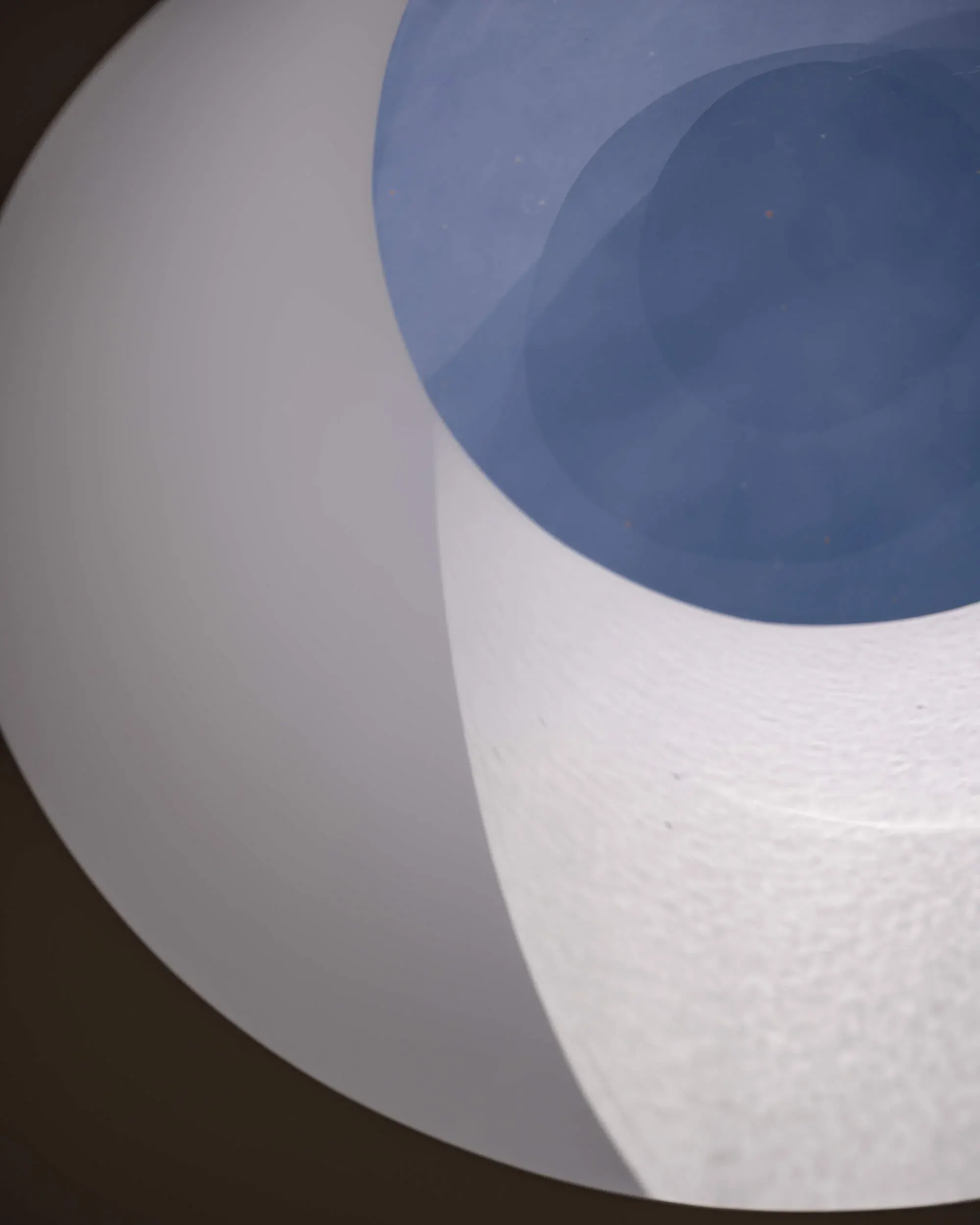 The circular skylight well from below, its white curve cut against blue sky