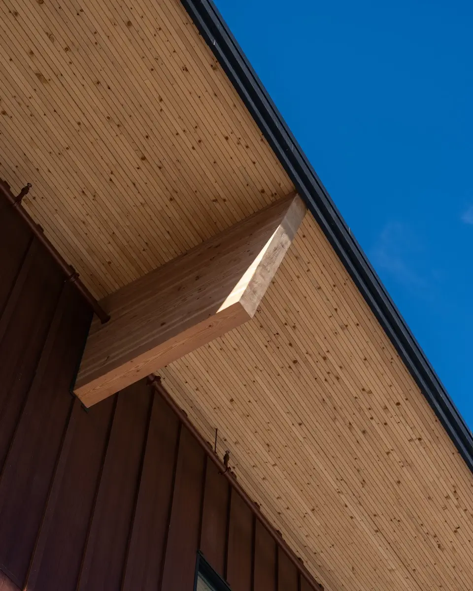 A timber beam meeting the underside of the roof against open sky