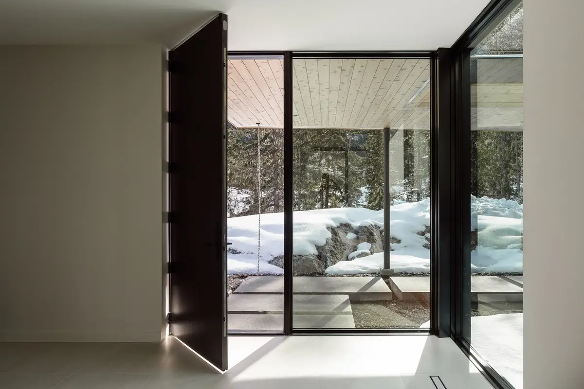 Pivot entry door standing open to a glazed corner and the snow outside