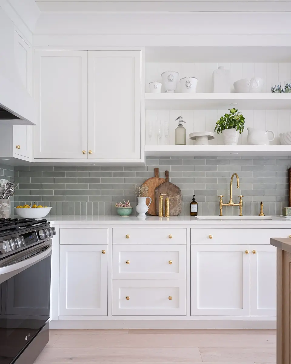 Range beside open shelves of white ceramics, a tall gold toned tap at the sink