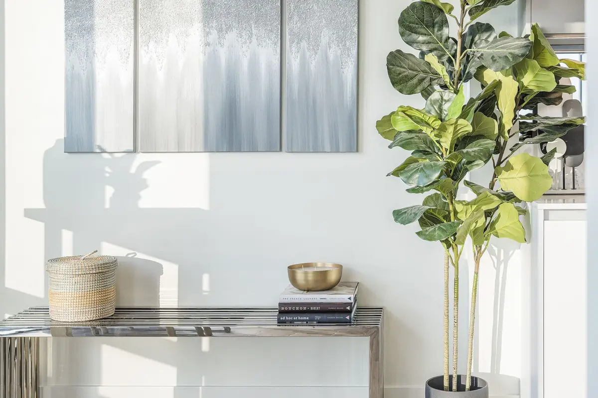 A slatted metal console under three blue and silver panels, a lidded basket and books