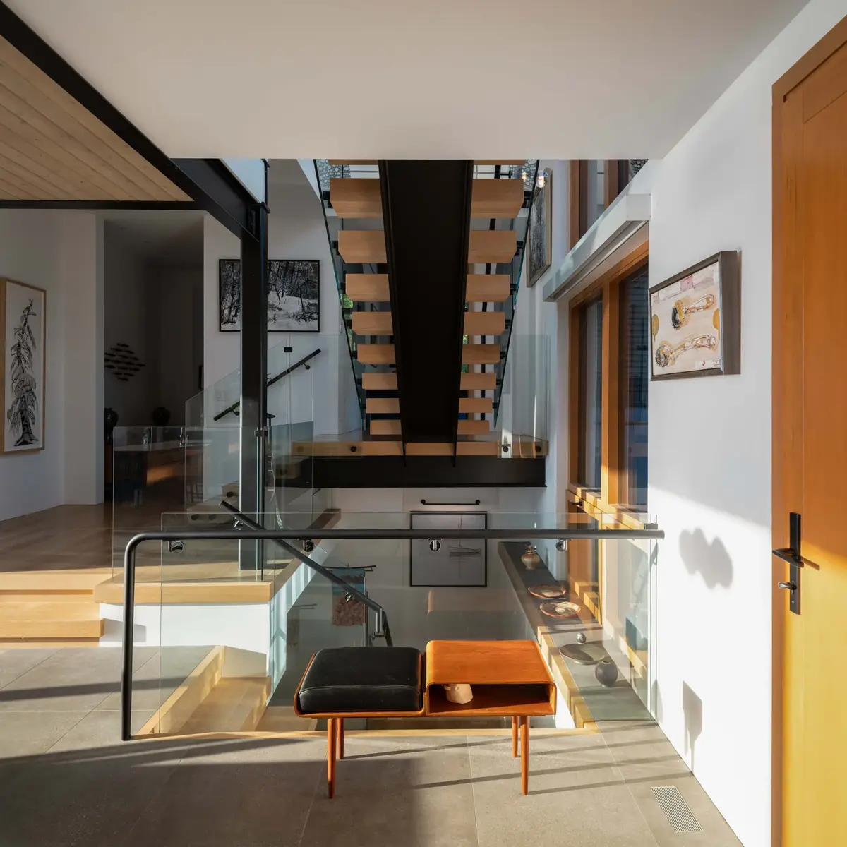Entry hall with a bench and an open stair behind a glass balustrade