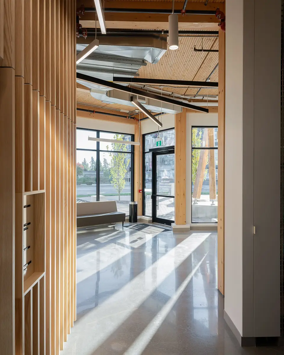 Lobby entrance with a slatted wood screen, sunlight striping the polished concrete floor