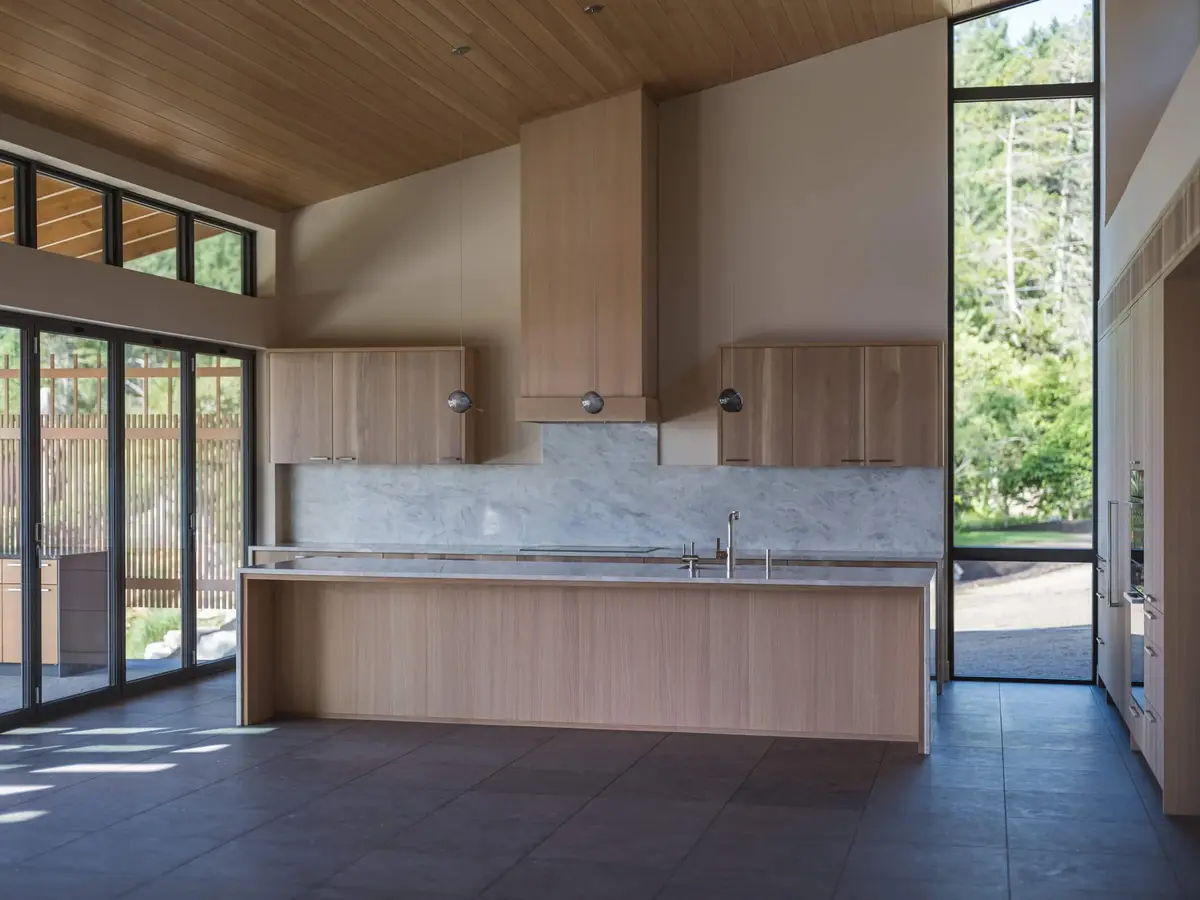 Kitchen elevation with a veined stone backsplash and hood, an island running in front