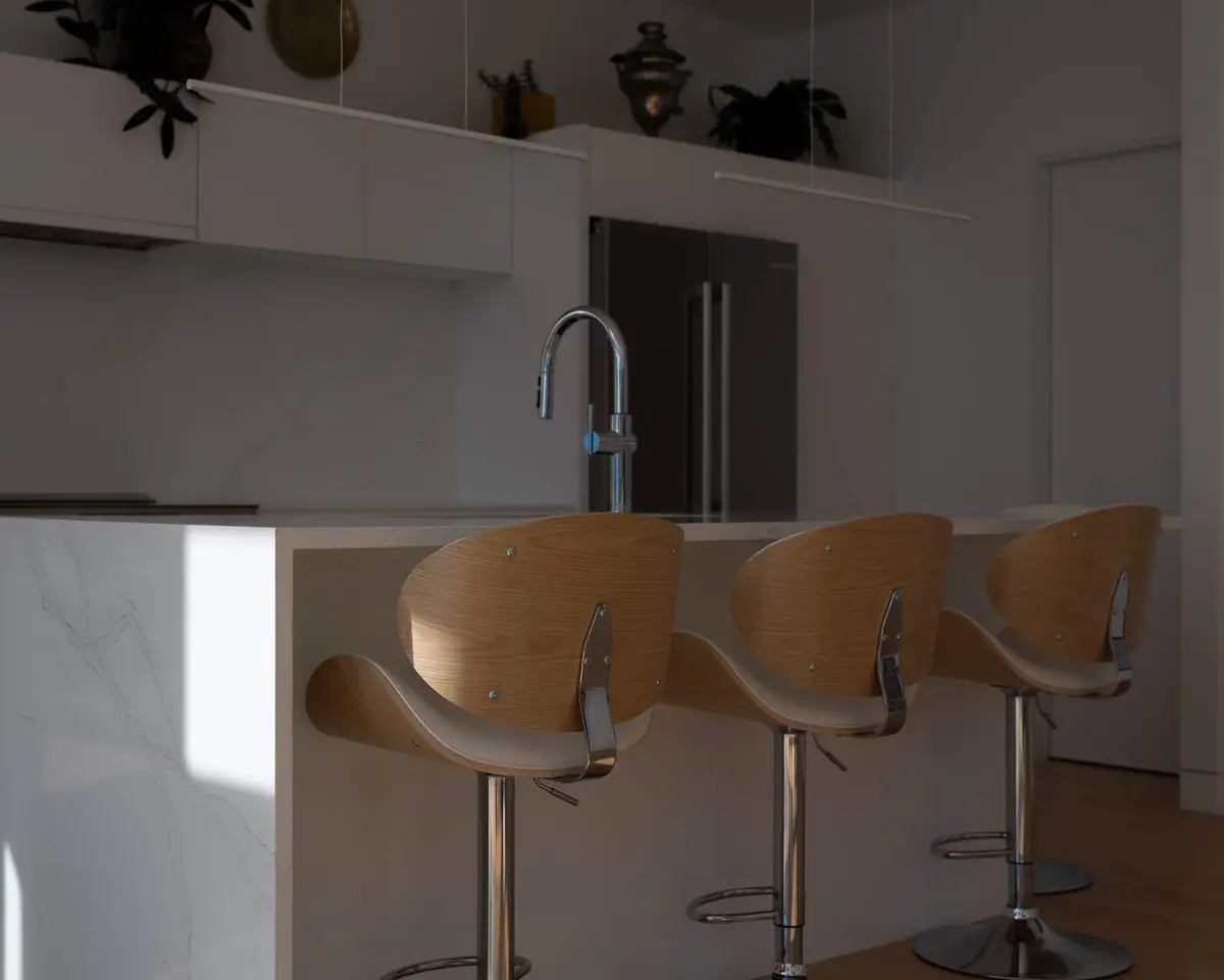 Three curved wood stools at the island counter, a tall fridge beyond