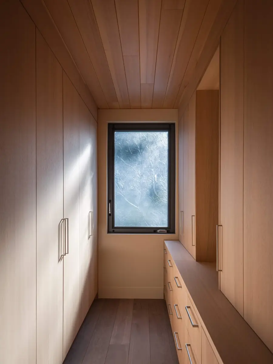 Wood lined dressing room with a window at the end and a long run of drawers