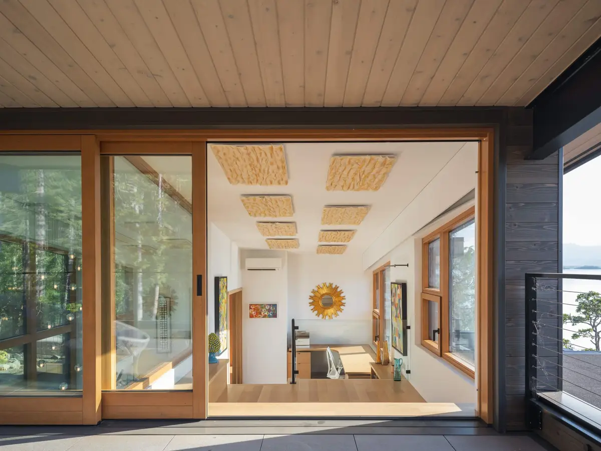 Office through a wide sliding door, framed art and woven ceiling panels beyond