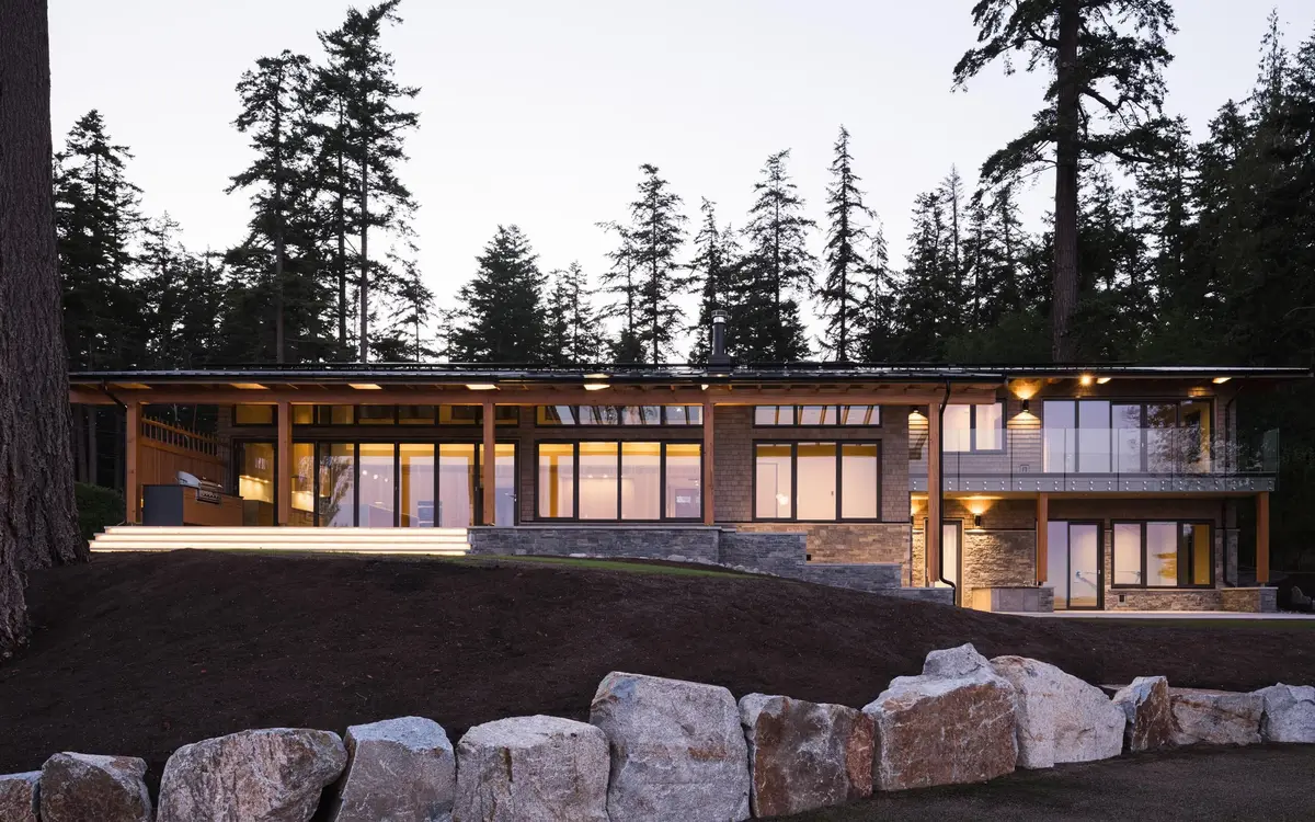 The long elevation lit at dusk above a bank of boulders and dark earth