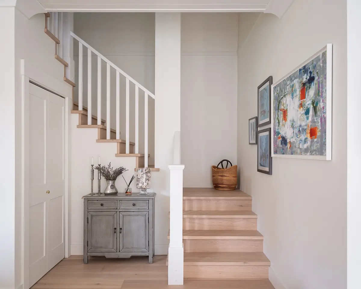 Entry hall with a white balustered stair, a grey sideboard and a large abstract painting