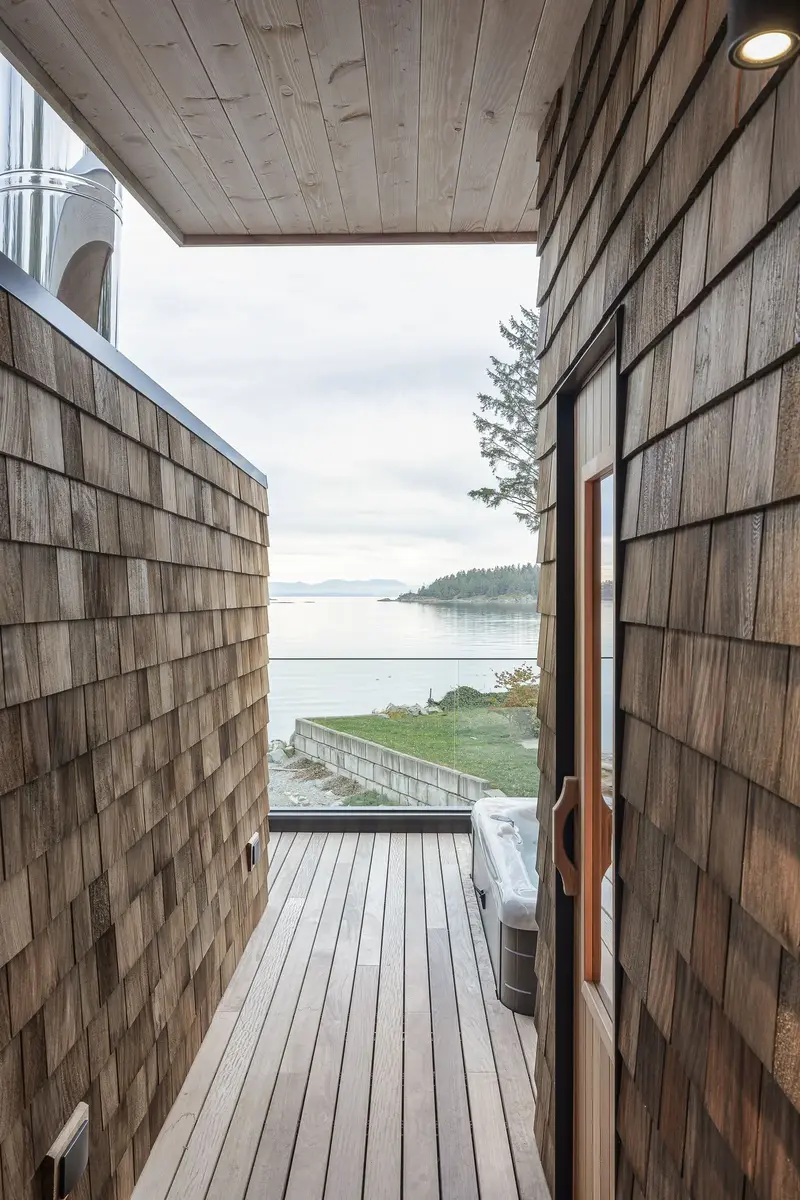 A deck passage past the sauna door, hot tub and open water at the end