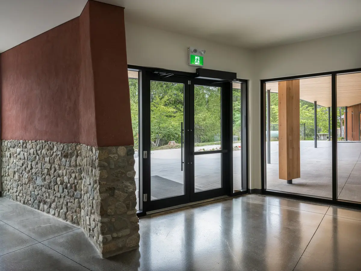 Lobby with glazed doors either side, the stone based wall meeting polished concrete