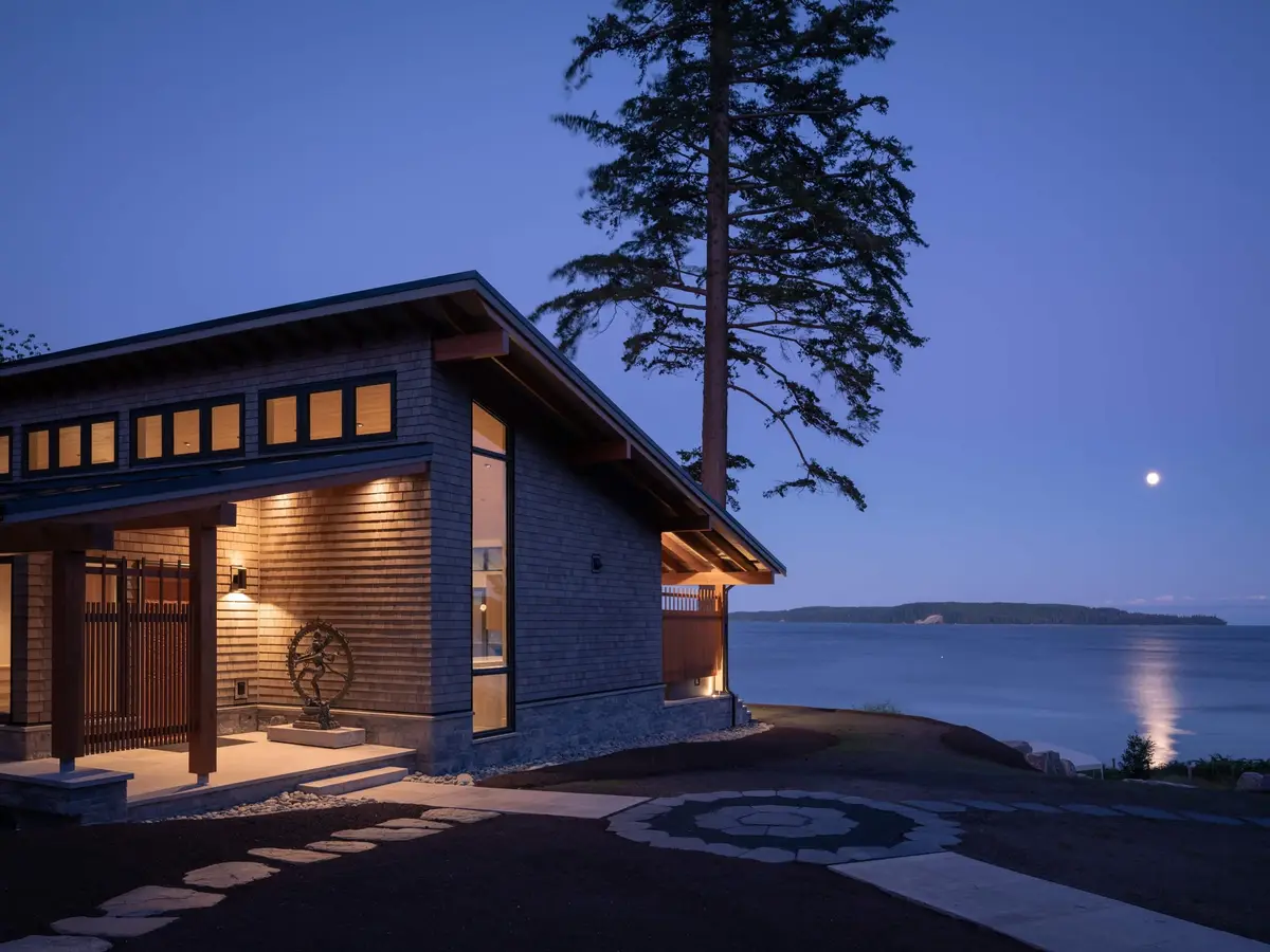 Desolation Sound residence at blue hour, the lit wing under its low roof and a rising moon