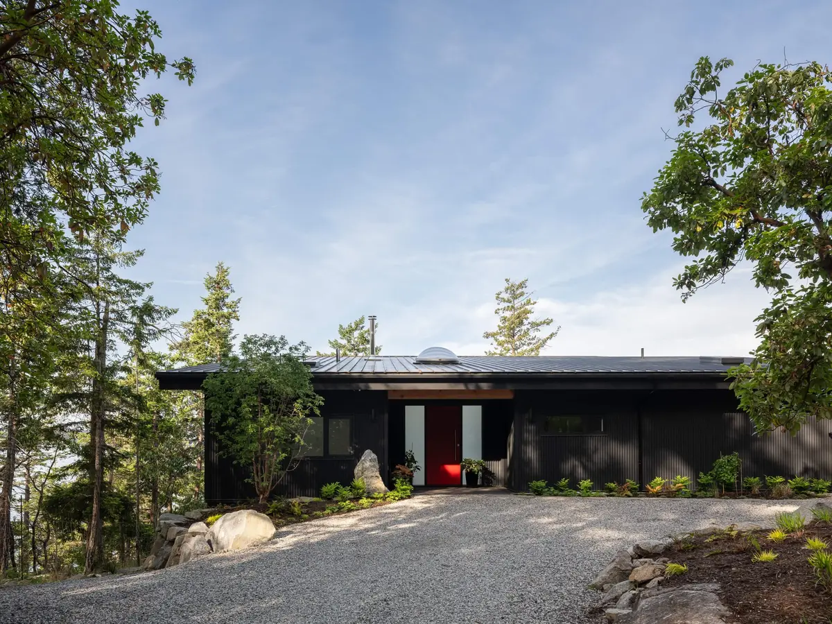 The long entry elevation behind a gravel court, a red door at its centre