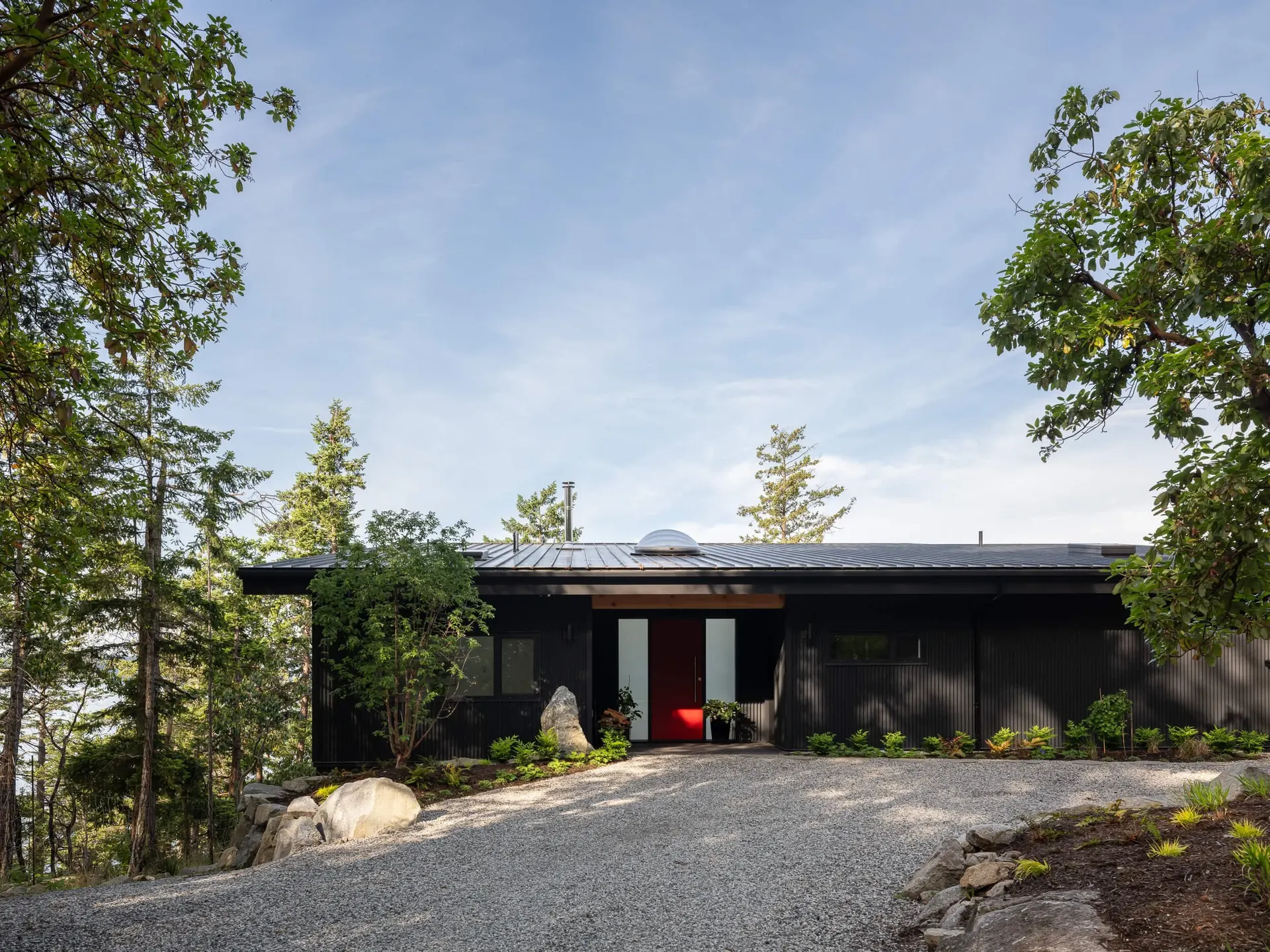 The long entry elevation behind a gravel court, a red door at its centre