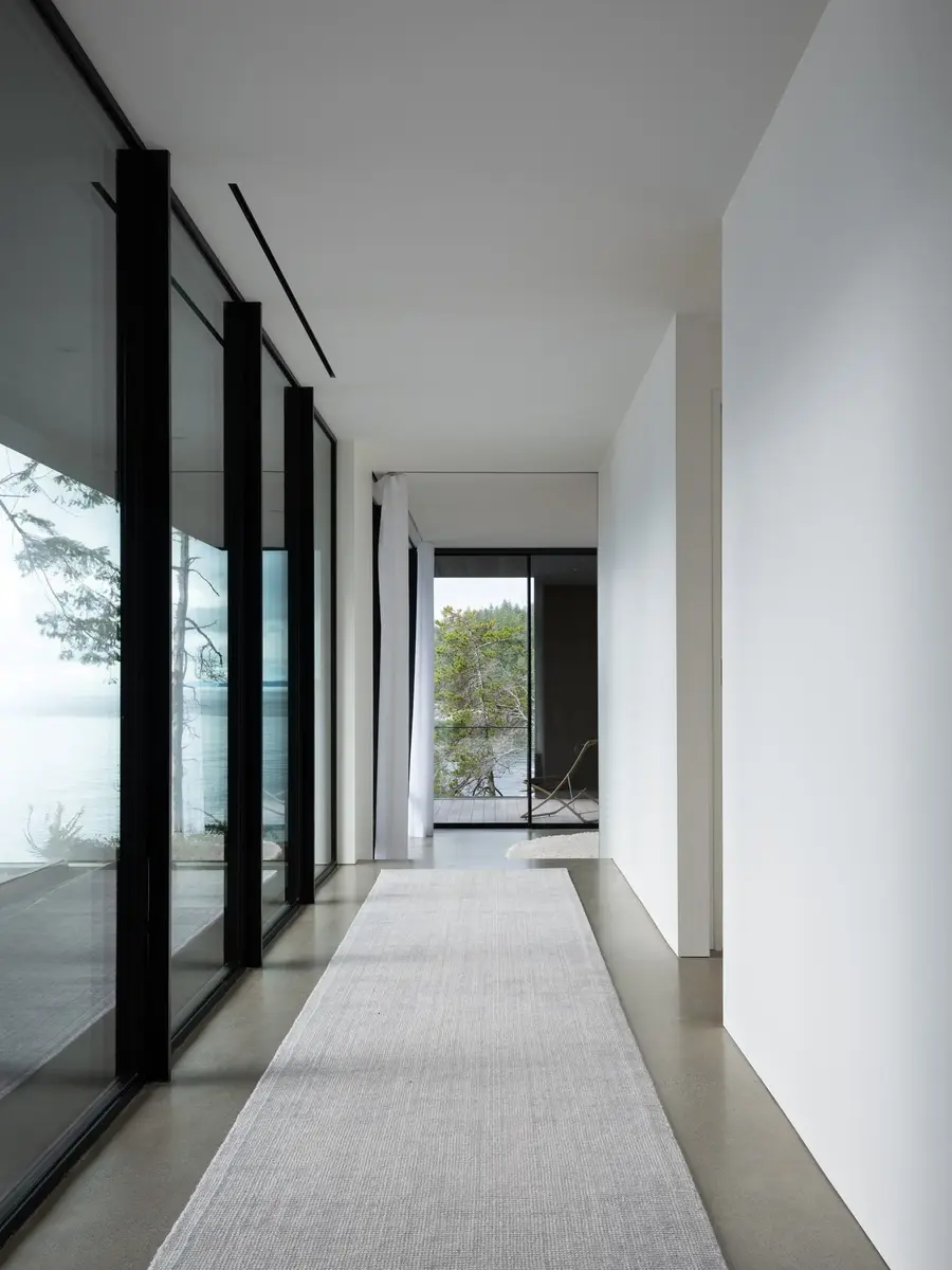 Corridor along full height glazing, a pale runner laid on the polished concrete floor