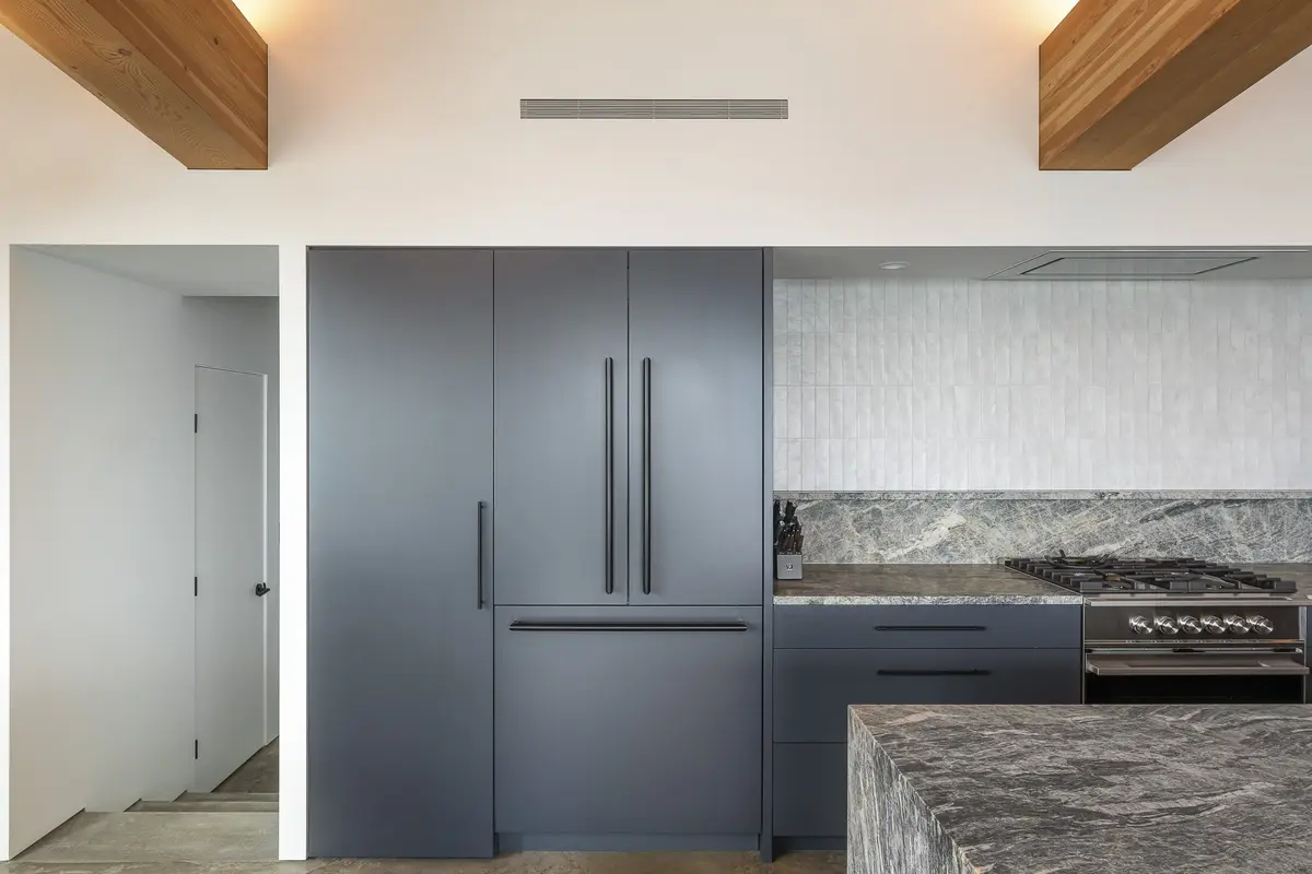Tall dark cabinets and refrigerator beside the range, doorway to the hall at left