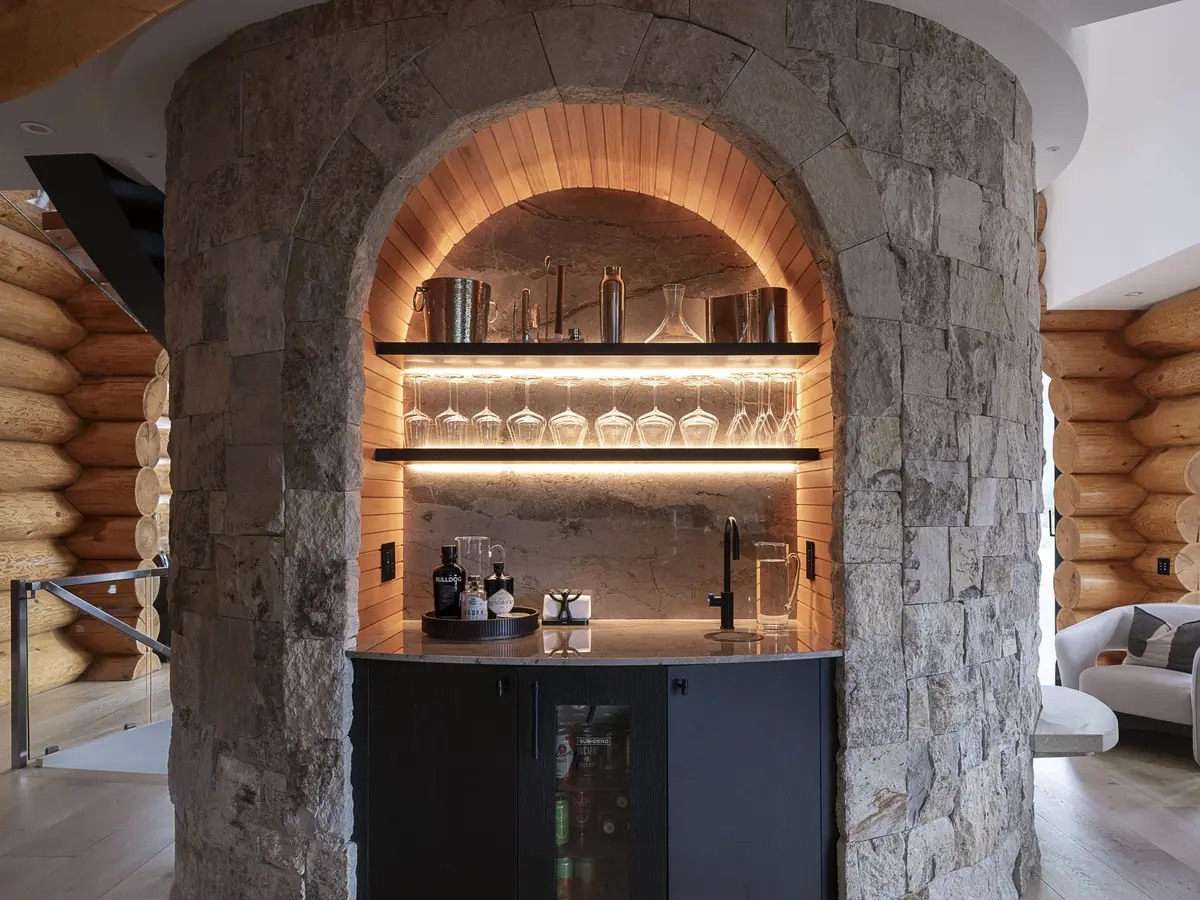 Bar set into an arched alcove in a stone wall, lit shelves of glassware above